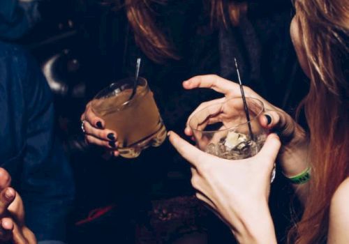 People are enjoying drinks and laughing in a lively setting, showing a close interaction and festive atmosphere.