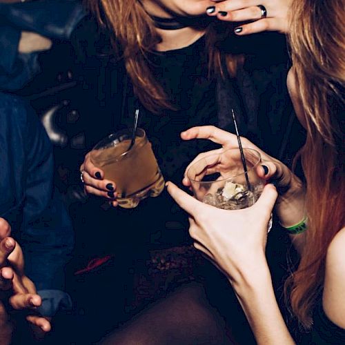 People are enjoying drinks and laughing in a lively setting, showing a close interaction and festive atmosphere.