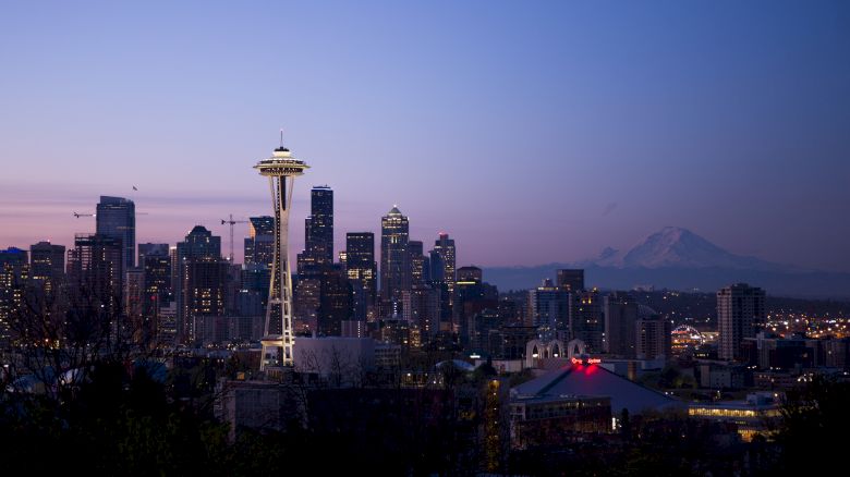 A scenic view of Seattle's skyline at dusk, featuring the Space Needle and Mount Rainier in the background.